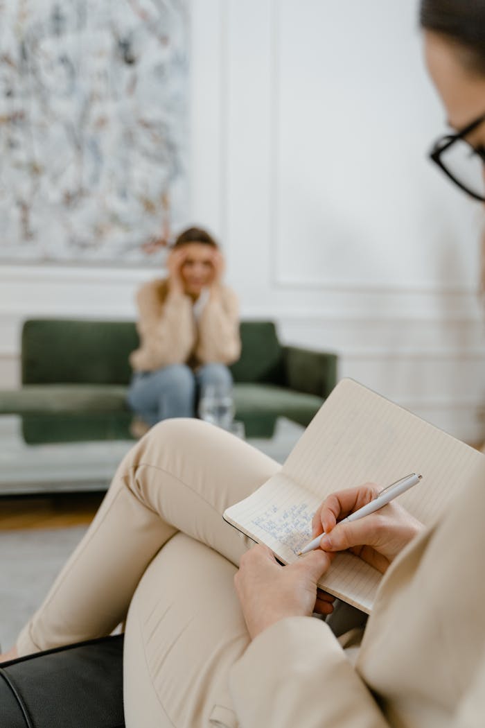 services-03 A therapist takes notes in a modern office setting during a therapy session with a patient.